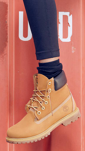 A close-up of an iconic women's Timberland wheat and black boot paired with cropped black skinny jeans.