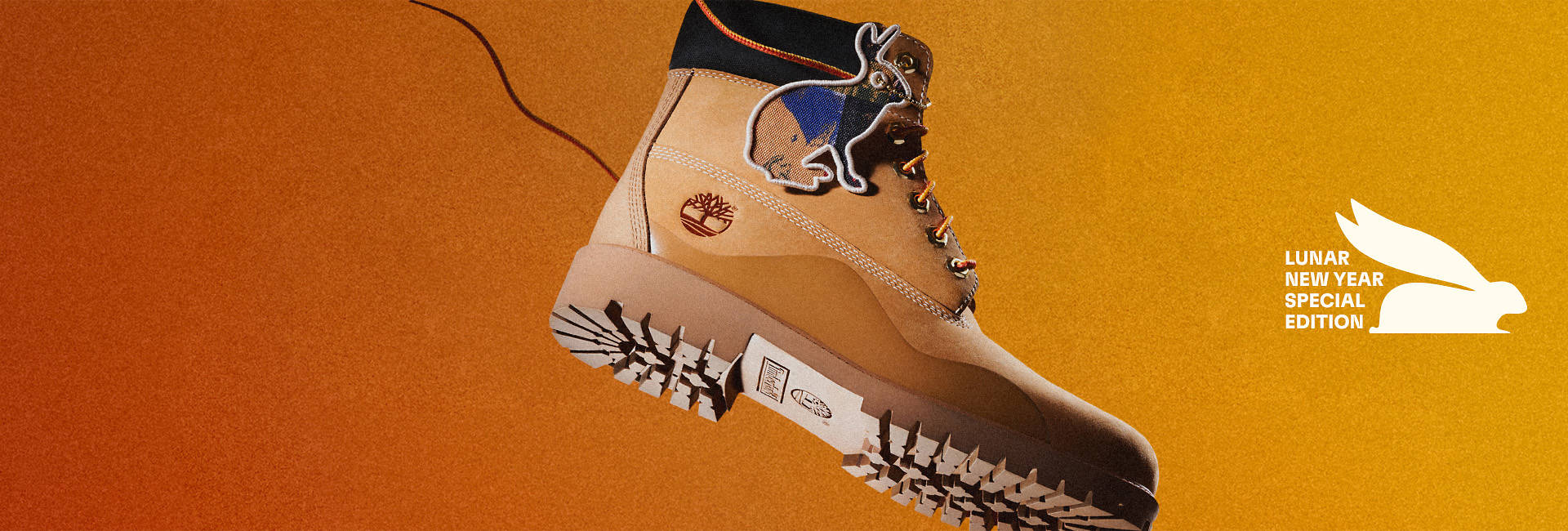 Image of a wheat colored Men's Timberland® Heritage 6-Inch Waterproof boot with rabbit outline hangtag and black collar, flying through the air on a downward trajectory against an orange gradient background.