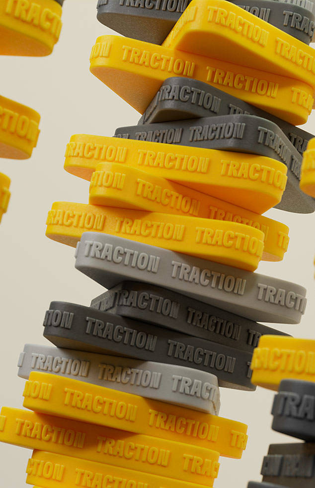 Image of an abstract stack of rubber triangles with the word "traction" printed on the sides.