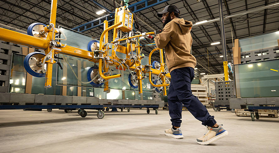 Image of a warehouse worker using heavy machinery, wearing a brown Timberland hoodie, dark blue Timberland jogger work pants and gray/white Timberland work shoes.