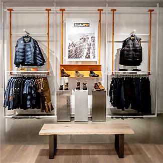 Image of a wall display inside of a Timberland store, where there are several Timberland PRO items on display including jackets, vests, long sleeve shirts and boots.