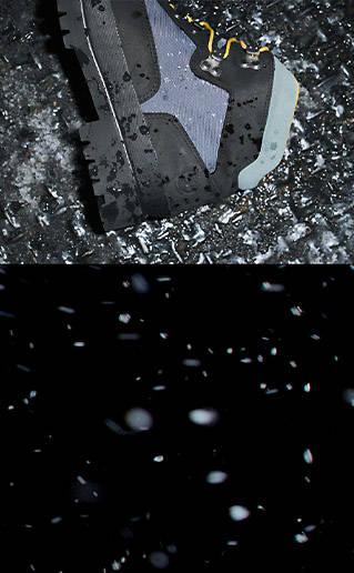 Overhead view of a gray and black Timberland™ boot on it's side with rain drops covering it, while on top of a silver sewer grate.