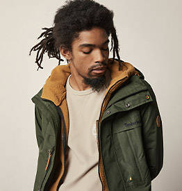 Image of a man in braids in an olive green jacket.