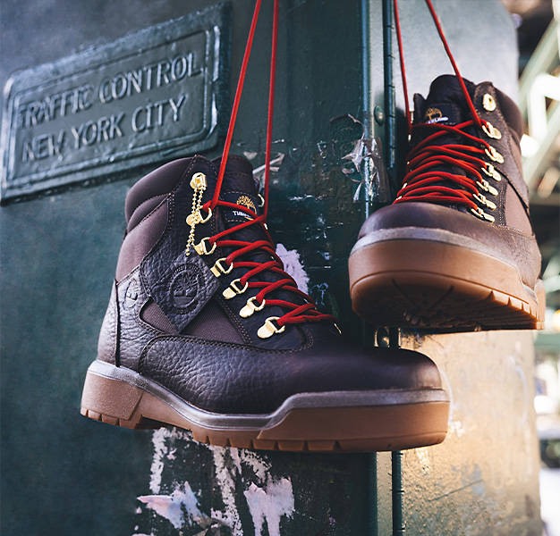 Image of a pair of hanging Timberland Field Boots on a traffic control metal box located on the streets of New York City