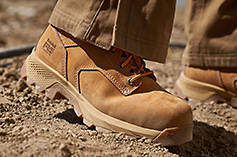 Image from the lower shins to the ground of a pair of wheat Timberland PRO boots matched with a pair of brown jeans.