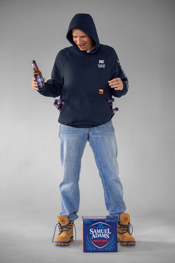 Man wearing Men's Sam Adams x Timberland PRO Beerproof Hoodie and Men's Sam Adams x Timberland PRO Direct Attach Beerproof Boots while holding a Samuel Adam's Lager which he grabbed from this Samuel Adam's Lager 12-Pack. Swipe right to get to the next product in the image carousel.