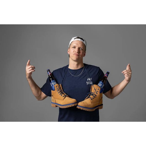 Man wearing the Men's Sam Adams x Timberland PRO Beerproof T-Shirt. Wrapped over his neck by the shoelaces are a pair of en's Sam Adams x Timberland PRO Direct Attach Beerproof Boots. Swipe right to get to the next product in the image carousel.
